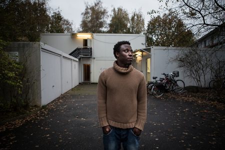 Ibrahim aus Ghana steht vor seiner Containerunterkunft am Stadtrand. Er ist Sohn einer muslimischen Mutter und eines christlichen Vaters. „Manchmal hat man das Gefühl nirgends willkommen zu sein. Aus Libyen mussten wir fliehen, aus Italien hat man uns weggeschickt und hier will man uns auch nicht haben.“