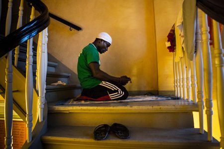 Zakaria aus Ghana betet auf den Kirchentreppen. Die muslimischen Flüchtlinge teilen sich einen Gebetsteppich den sie abwechselnd benutzen.Sankt Pauli Kirche, Lampedusa in Hamburg
